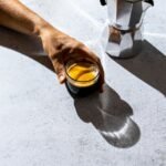 person holding clear glass mug with brown liquid
