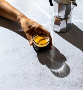 person holding clear glass mug with brown liquid