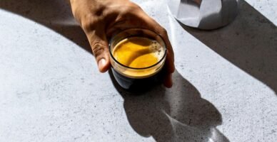 person holding clear glass mug with brown liquid